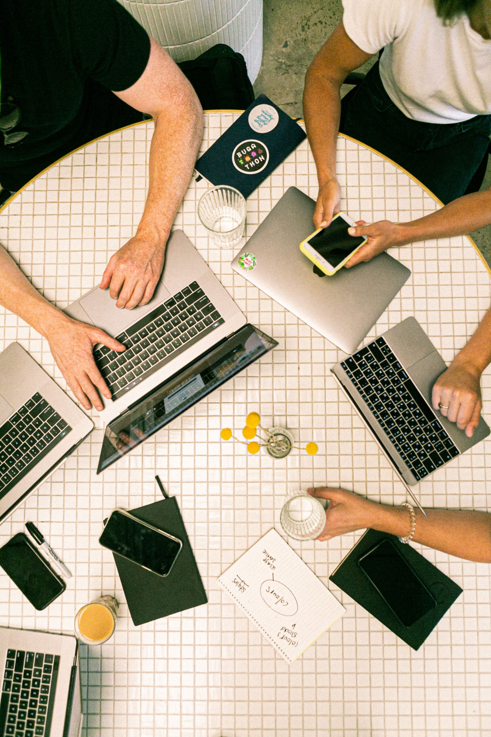 Four people working on laptops around a table